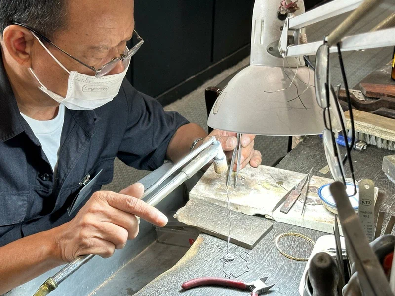 Close-up of a master craftsman setting a stone under a workbench lamp